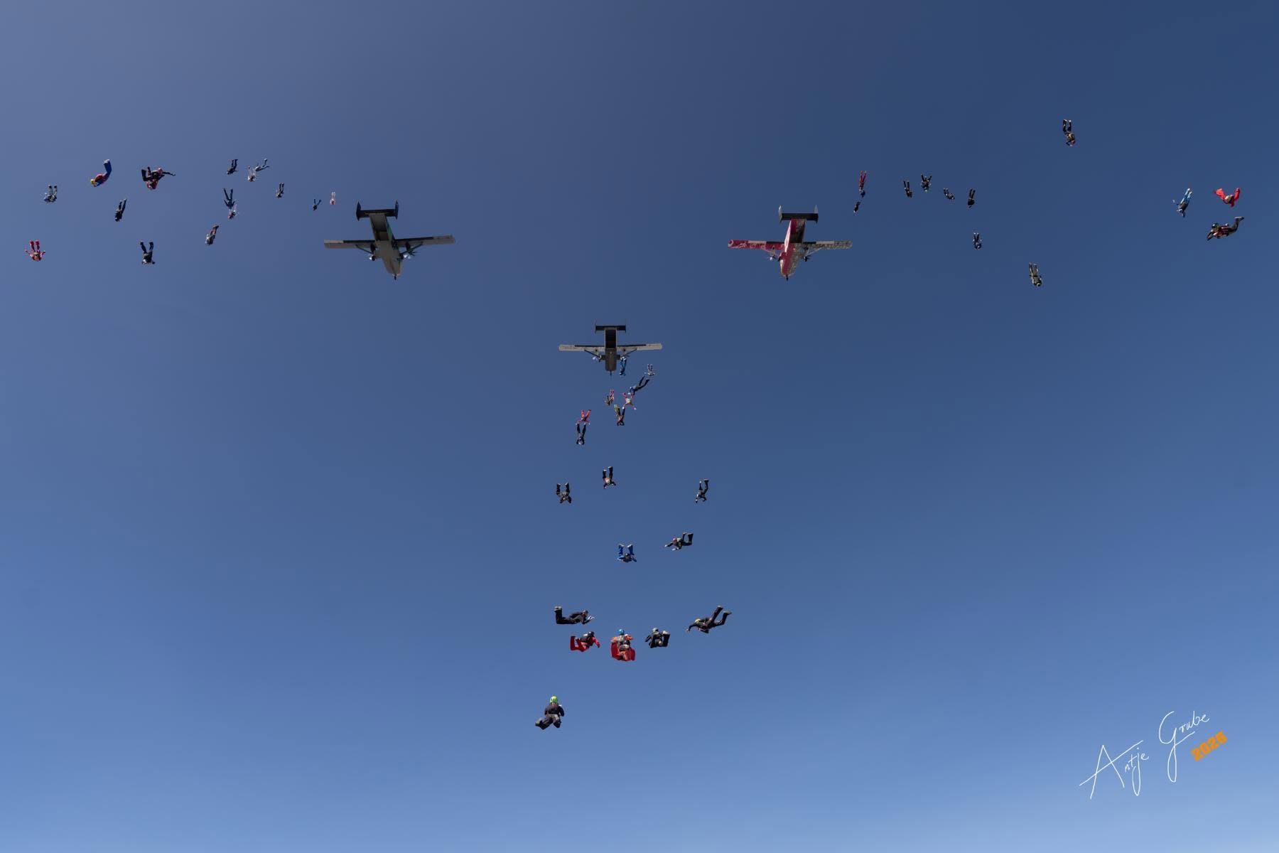 Fallskärmshoppare och flygplan högt på blå himmel